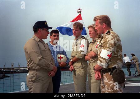 SENIOR CHIEF Hospital Corpsman W. C. Tutcher, Left, und Hospital Corpsman 3. Klasse Frank J. Chaves, Zweiter von links, vergleichen Sie Notizen mit niederländischem medizinischem Personal auf dem Deck des niederländischen Schnellkampfschiffs HNLMS ZUIDERKRUIS (A832), während das Schiff während der Operation Desert Storm im Hafen liegt. Tutcher und Chaves dienen an Bord der geführten Raketenfregatte USS MCINERNEY (FFG-8). Betreff Operation/Serie: WÜSTENSTURM Land: Bahrain (BHR) Stockfoto