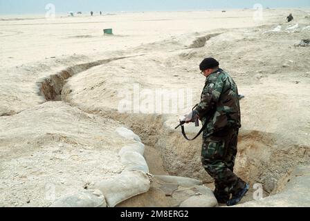 Ein Mitglied einer der Spezialeinheiten der Koalition inspiziert während der Operation Desert Storm einen irakischen Graben nach verbliebenen feindlichen Soldaten. Betroffene Operation/Serie: WÜSTENSTURM Land: Unbekannt Stockfoto