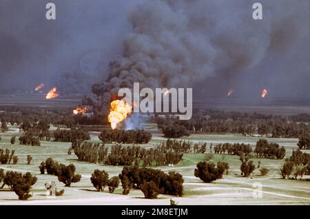 Ölquellen verbrennen außer Kontrolle und verdunkeln den Himmel mit Rauch, nachdem sie durch den Rückzug der irakischen Streitkräfte während der Operation Desert Storm in Brand gesetzt wurden. Betreff Betrieb/Serie: WÜSTENSTURM Land: Kuwait(KWT) Stockfoto