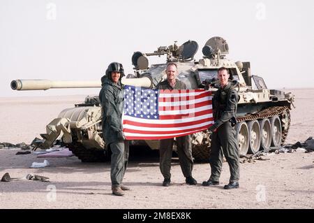 SGT. D. McDuade, CHIEF Warrant Officer P. Wade und 1. LT. Merkile, UH-60 Black Hawk (Blackhawk), Hubschrauberbesatzungsmitglieder von Co B, 7. Mrd. US-Dollar, 158. US-Dollar Army Reserve, halten Sie eine US-Flagge vor einen irakischen T-55 Hauptschlachtpanzer auf den Rumaila Ölfeldern, nachdem sich die irakischen Truppen während der Operation Desert Storm aus Kuwait zurückgezogen haben. Betreff Operation/Serie: WÜSTENSTURM Land: Irak (IRQ) Stockfoto