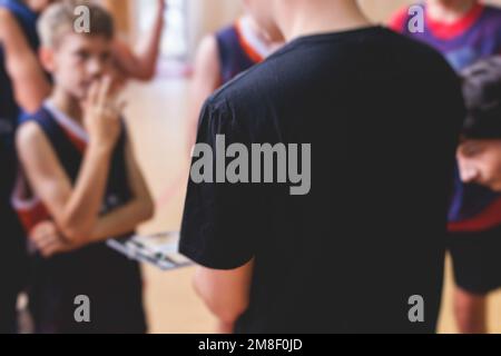 Junge Basketballmannschaft mit Trainer, Kindergruppe, die trainiert, Team spricht mit Trainer Trainer, Basketball-Trainer Stockfoto