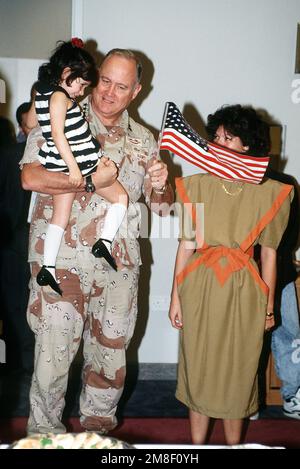 Bei einem Empfang nach einer Preisverleihung in den USA Botschaft, GEN. Norman Schwarzkopf, Oberbefehlshaber, USA Zentralkommando, hält ein Mädchen fest. Bei der Zeremonie präsentierte Schwarzkopf MAJ. Richard Holley, befehlshabender Offizier der USA Büro für militärische Zusammenarbeit, Bahrain, mit dem Joint Meritorious Unit Award für die Leistung seiner Einheit während der Operation Desert Storm. Betreff Operation/Serie: WÜSTENSTURMBASIS: Manama-Land: Bahrain (BHR) Stockfoto