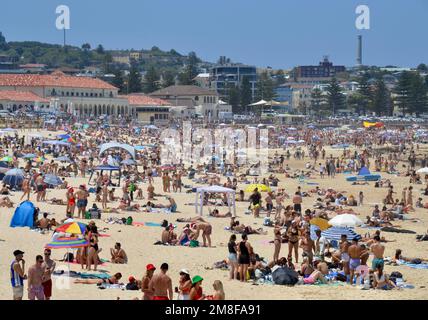 Der gepackte Bondi Beach vor Sydney am ersten Weihnachtsfeiertag ist voller Rucksacktouristen, die in Santa Mützen gekleidet sind und Tsunbaking, Schwimmen und australischen Sonnenschein genießen Stockfoto