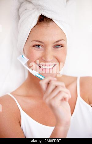Zahnhygiene ist ihr wichtig. Eine reizende junge Frau, die nach einer erfrischenden Dusche eine Zahnbürste in der Hand hält. Stockfoto