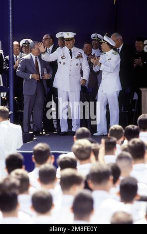 GENERAL H. Norman Schwarzkopf, Zentrum, Oberbefehlshaber, USA Zentralkommando, würdigt den Applaus der Menge, die an der Abschlussfeier und der Provisionszeremonie für die Akademie-Klasse 1991 teilnahm. Schwarzkopf wird flankiert von Marinesekretär H. Lawrence Garrett III, Left, und RADM Virgil L. Hill Jr., Right, Superintendent der Marineakademie. Basis: US Naval Academy, Annapolis Bundesstaat: Maryland (MD) Land: Vereinigte Staaten von Amerika (USA) Stockfoto