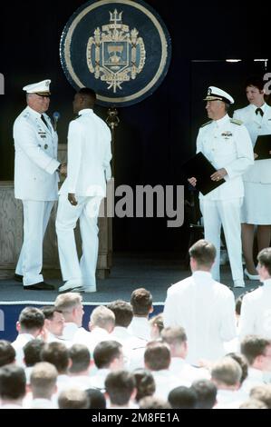 Ein 1991 abgeschlossener Fähnrich schüttelt dem Gastredner Army GEN H. Norman Schwarzkopf, Oberbefehlshaber der USA, die Hand Das Zentralkommando, bevor er sein Diplom vom Naval Academy Supervisor RADM Virgil L. Hill Jr. erhielt Basis: US Naval Academy, Annapolis Bundesstaat: Maryland (MD) Land: Vereinigte Staaten von Amerika (USA) Stockfoto