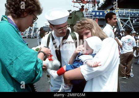 Ein dem Flugzeugträger USS RANGER (CV-61) zugeteilter Seemann wird nach der Ankunft des Schiffes am Pier mit seiner Frau und seinem Kind wiedervereint. Der RANGER ist nach seiner Entsendung in die Region des Persischen Golfs für Operation Desert Shield und Operation Desert Storm nach North Island zurückgekehrt. Betreff Operation/Serie: DESERT SHIELD DESERT STORM Base: Naval Air Station, North Island State: California(CA) Country: United States of America (USA) Stockfoto