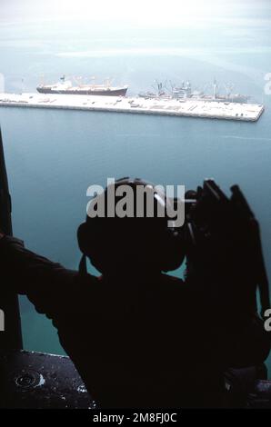 Ein Videokameramann filmt Ladevorgänge aus einem Hubschrauber wie das vom Militärkommando gecharterte Frachter CAPE BON (T-AK-5059) und ein Handelsschiff am Pierside. Die Schiffe nehmen Ausrüstung und Kampfmittel auf, um nach Operation Desert Storm in die Vereinigten Staaten umgesiedelt zu werden. Betreff Operation/Serie: WÜSTENSTURM Land: Saudi-Arabien (Sau) Stockfoto