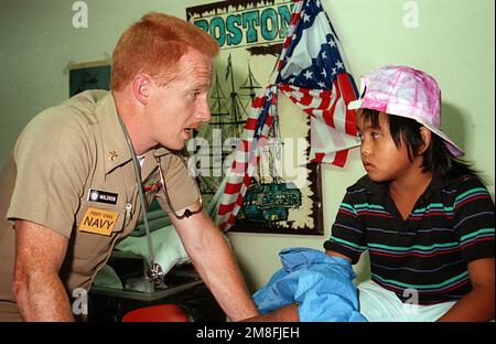 DER CHEFKRANKENHAUS-Corpsman Dirk Waldron versichert ein Kind in einem medizinischen Behandlungszentrum, das für Evakuierte von der Marinestation, Subic Bay und Naval Air Station, Cubi Point eingerichtet wurde. Die Evakuierung findet im Rahmen der Operation Fiery Vigil statt, die darauf abzielt, zivile und militärische Mitarbeiter und ihre Angehörigen nach dem Ausbruch des Mount Pinatubo am 10. Juni von den Philippinen zu entfernen. Betreff Operation/Serie: FEURIGE WACHE Stützpunkt: Luftwaffenstützpunkt Travis Bundesstaat: Kalifornien(CA) Land: Vereinigte Staaten von Amerika(USA) Stockfoto