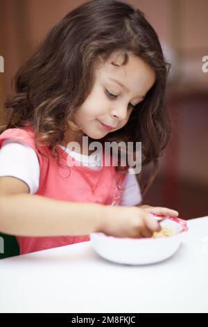 Ich genieße ihr Mittagessen. Vorschulmädchen isst etwas in einer Schüssel. Stockfoto