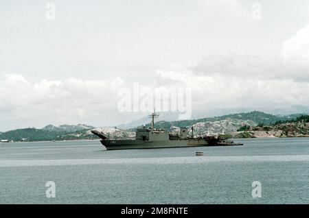 Ein großer Hafenschlepper kommt an das Tanklandeschiff USS PEORIA (LST-1183) vorbei, wenn das Schiff am Marinestützpunkt ankommt. Die vulkanische Asche aus dem jüngsten Ausbruch des Mount Pinatubo bedeckt einen Großteil der Landschaft im Hintergrund. Basis: Marinestützpunkt, Subic Bay Staat: Luzon Land: Philippinen (PHL) Stockfoto