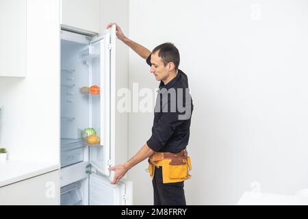 Junge männliche Handwerker zur Festsetzung der Kühlschrank in der Küche Stockfoto