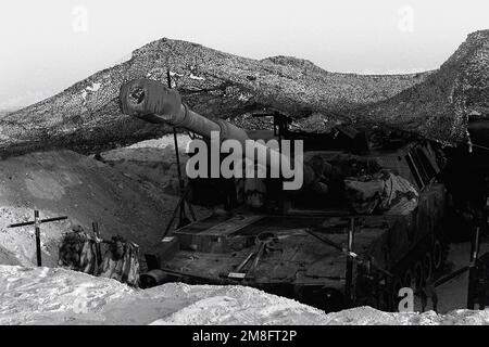Ein M-109A1 selbstfahrender 155mm-Howitzer sitzt in einer Waffengrube unter einem Tarnnetz während der Operation Desert Shield. Der Haubitzer ist dem 5. Bataillon, 11. Marines zugeteilt. Betreff Operation/Serie: WÜSTENSCHILD Land: Saudi-Arabien (Sau) Stockfoto
