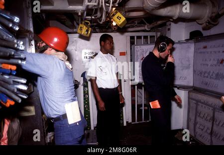 Ein westafrikanischer Offizier beobachtet, wie zwei Petty Officers während einer allgemeinen Quartierübung an Bord des Panzerlandungsschiffs USS BARNSTABLE COUNTY (LST-1197) in einem Reparaturraum arbeiten. Mehrere Offiziere aus westafrikanischen Ländern sind an Bord des BARNSTABLE COUNTY als Beobachter auf seiner Reise von Brasilien in den Kongo zu Beginn der Westafrika-Trainingskreuzfahrt 1991. Land: Atlantik (AOC) Stockfoto