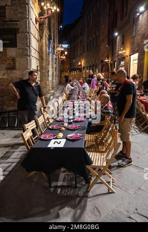 Siena, Italien - August 15 2022: Das große Contrada-Dinner der Civetta oder der kleinen Eule Contrada am Abend vor dem Palio dell Assunta auf der Piazza to Stockfoto