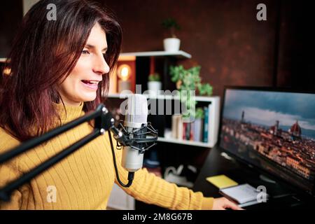 Frau nimmt Podcast mit Mikrofon und Computern aus ihrem selbstgemachten Studio auf. Stockfoto