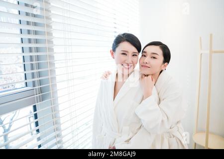 Mutter und Tochter, zwei Leute im Bademantel saßen am Fenster Stockfoto