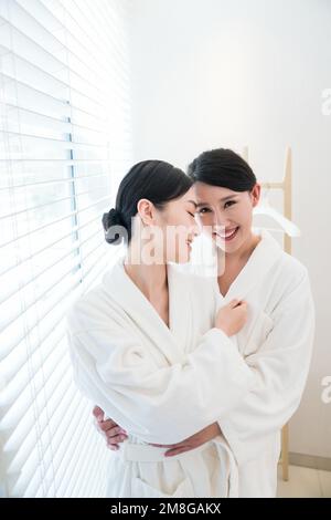 Mutter und Tochter, zwei Leute im Bademantel saßen am Fenster Stockfoto