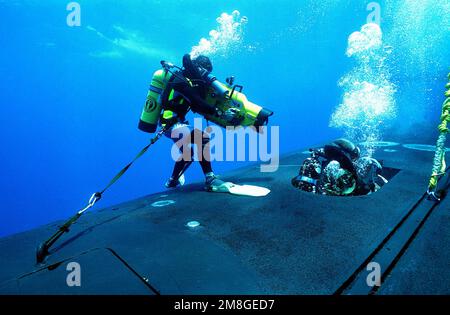 Fotograf's Mate 1. Class/Diver Slater filmt ein Mitglied eines Navy Sea-Air-Land (SEAL) Teams, als er aus einer Luke im vorderen Rumpf der nuklearbetriebenen Sumbarine USS JAMES K. POLK (SSBN-645) herauskommt. Der Kameramann filmt die Mitglieder DES SEAL-Teams, während sie an den Aussperrungsverfahren vor der Küste von Key West, Florida, teilnehmen, während der Übung Phantom Striker. Betreff Operation/Serie: PHANTOM STRIKER Country: Atlantik (AOC) Stockfoto