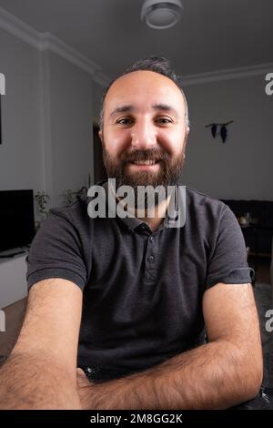 Mann hält Smartphone an der Hand, um Videoanrufe anzusehen. Vertikales Bild eines Geschäftsmanns. Lächelnder junger Kaukasier, männlicher Talk auf der Webcam. Stockfoto