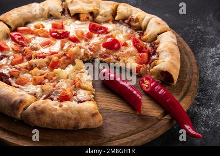 Indische Pizza mit Tomaten und Paprika aus nächster Nähe. Traditionelle indische Pizza auf Brot-Fladenbrot Stockfoto