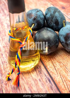 Ein vertikaler Schuss des Pflaumenbranntweins mit Pflaumen auf dem Holztisch Stockfoto