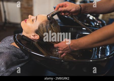 Friseur wäscht die Haare des Kunden im Salon, Seitenansicht, mittlere Nahaufnahme, Schönheitskonzept. Hochwertiges Foto Stockfoto