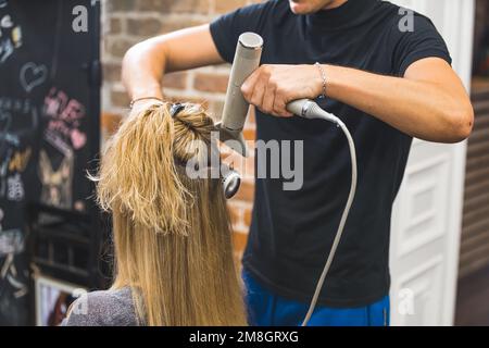 Nahaufnahme eines Friseursalons mit Kammaufsatz und Fön und trocknendem blondem Haar der Frau. Hochwertiges Foto Stockfoto