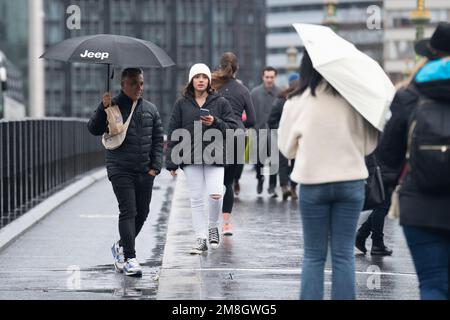 Die Leute laufen im Regen auf der Westminster Bridge, im Zentrum von London. Foto: Samstag, 14. Januar 2023. Stockfoto