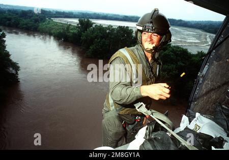 PERSONAL SGT. Fred Miller von der Army National Guard steht am Rand eines UH-1 Hubschraubers, während der Hubschrauber über das Hochwasser fliegt. Der Hubschrauber trägt Sandsäcke zur Kläranlage des Wasserwerks (genaues Datum unbekannt). Basis: Des Moines Staat: Iowa (IA) Land: Vereinigte Staaten von Amerika (USA) Stockfoto