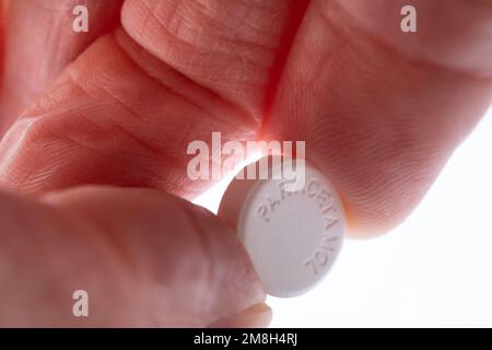 Paracetamol-Tablette zwischen Zeigefinger und Daumen. Medikamente, Schmerzmittel (Schmerzmittel) zur Linderung und Behandlung von Kopfschmerzen, Zahnschmerzen, Rücken, Erkältungen oder Grippe Stockfoto