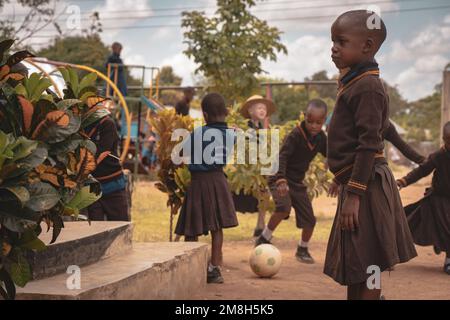 25. März 2022 - Mwanza, Tansania - Kinder, die auf dem Schulgelände spielen und Spaß haben. Laufen, Seil überspringen, Football spielen. Stockfoto