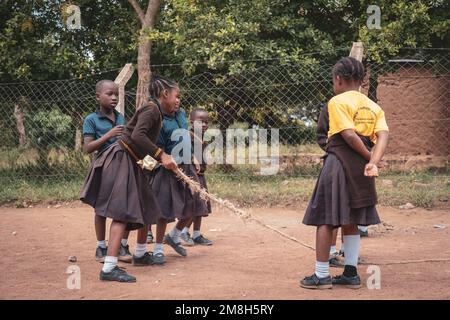 25. März 2022 - Mwanza, Tansania - Kinder, die auf dem Schulgelände spielen und Spaß haben. Laufen, Seil überspringen, Football spielen. Stockfoto