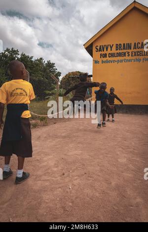 25. März 2022 - Mwanza, Tansania - Kinder, die auf dem Schulgelände spielen und Spaß haben. Laufen, Seil überspringen, Football spielen. Stockfoto