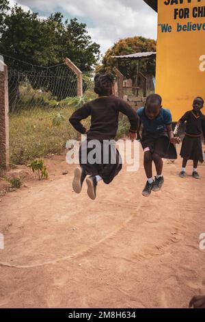 25. März 2022 - Mwanza, Tansania - Kinder, die auf dem Schulgelände spielen und Spaß haben. Laufen, Seil überspringen, Football spielen. Stockfoto