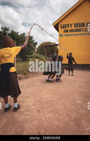 25. März 2022 - Mwanza, Tansania - Kinder, die auf dem Schulgelände spielen und Spaß haben. Laufen, Seil überspringen, Football spielen. Stockfoto