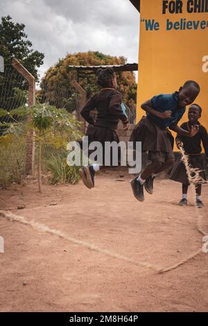 25. März 2022 - Mwanza, Tansania - Kinder, die auf dem Schulgelände spielen und Spaß haben. Laufen, Seil überspringen, Football spielen. Stockfoto