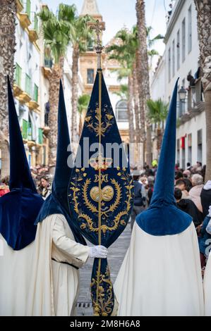 Menschen in traditionellen Kleidern, die einen capriote werdeten, oder Spitzhut bei einer Osterparade während der Heiligen Woche oder Semana Santa in Cadiz, Spanien Stockfoto