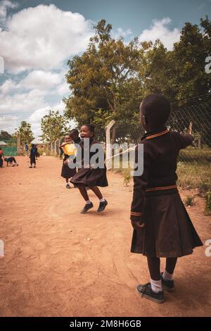 25. März 2022 - Mwanza, Tansania - Kinder, die auf dem Schulgelände spielen und Spaß haben. Laufen, Seil überspringen, Football spielen. Stockfoto