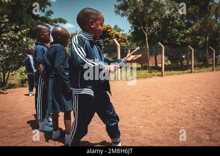 25. März 2022 - Mwanza, Tansania - Kinder, die auf dem Schulgelände spielen und Spaß haben. Laufen, Seil überspringen, Football spielen. Stockfoto