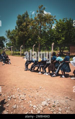 25. März 2022 - Mwanza, Tansania - Kinder, die auf dem Schulgelände spielen und Spaß haben. Laufen, Seil überspringen, Football spielen. Stockfoto