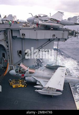 Ein Besatzungsmitglied, das ein SD-1D-Flugzeug betreibt und einen Dolly beobachtet, positioniert ein taktisches elektronisches Kriegsgeschwader 138 (VAQ-138) EA-6B Prowler-Flugzeug in einem Aufzug des nukleargetriebenen Flugzeugträgers USS NIMITZ (CVN-68). Land: Pazifik (POC) Stockfoto