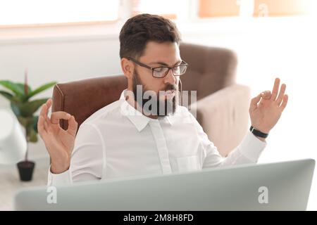 Ein hübscher junger Mann, der im Büro meditiert, Nahaufnahme Stockfoto