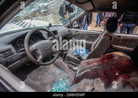 Dschenin, Palästina. 14. Januar 2023. Die Palästinenser inspizieren das Auto, in dem zwei Palästinenser von der israelischen Armee während ihrer Verfolgung getötet wurden, nachdem sie das Feuer auf einen Militärposten in der Stadt Jaba in der Nähe von Dschenin im besetzten Westjordanland eröffnet hatten. Kredit: SOPA Images Limited/Alamy Live News Stockfoto