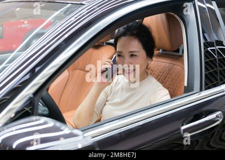 Die Geschäftsfrau saß im Auto und benutzte das Telefon Stockfoto