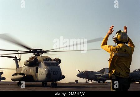 Ein Flugleiter signalisiert dem Piloten eines Marine Heavy Helicopter Squadron 362 (HMH-362) CH-53D Sea Hallion Helicopters, dass er sich auf den Start vom Cockpit des nukleargetriebenen Flugzeugträgers USS THEODORE ROOSEVELT (CVN-71) während Operation Deny Flight vorbereitet. Betreff Betrieb/Serie: DENY-FLUG Land: Adriatisches Meer Stockfoto