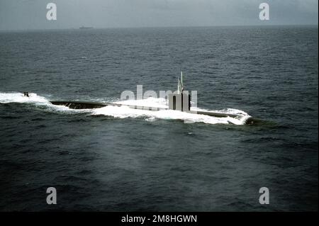 Ein seitlicher Blick aus der Luft auf das nuklearbetriebene U-Boot USS PASADENA (SSN-752), das in der Nähe von Hawaii unterwegs ist. Ein Flugzeugträger befindet sich im fernen Hintergrund. Land: Pazifik (POC) Stockfoto