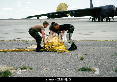 Wartungspersonal der 20. Bombenstaffel (2. Flügel), Barksdale, La., packt einen Fallschirm (Dragchute) aus einer B-52H Stratofestung während der Übung Mighty Force 93-6 ein. Eine B-52 mit dem Drachenschurre ist im Hintergrund. Der 2. Flügel wurde mit 12 Flugzeugen und 430 Personen eingesetzt. Die 20. Bombenstaffel hatte eine Startrate von 100 Prozent und eine pünktliche Rate von 98 Prozent während der Übung. Betreff Betrieb/Serie: MIGHTY FORCE 93-6 Basis: Roswell Bundesstaat: New Mexico (NM) Land: Vereinigte Staaten von Amerika (USA) Stockfoto
