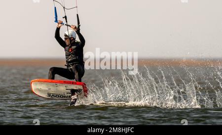 Ein Kiteboarder, der von einem Power Drachen über das Wasser gezogen wurde. New Brighton, Merseyside, England. Stockfoto