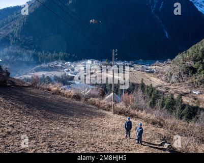 (230114) -- DEQEN, 14. Januar 2023 (Xinhua) -- Wangden (L) und sein Kollege Zhang Jincheng benutzen eine Drohne, um Stromübertragungsleitungen in Deqen County, Provinz Yunnan im Südwesten Chinas, am 10. Januar 2023 zu inspizieren. Wangden, 34, ist stellvertretender Direktor der Yunnan-Zweigstelle des Stromversorgungswerks Yanmen von China Southern Power Grid im Deqen County. 2015 wurde er beauftragt, Wartungsarbeiten in Yubeng zu übernehmen, einem Dorf am Fuße der schneebedeckten Berge. Als Yubengs dienstältester Energieversorger hat der Mann gewaltige Veränderungen im Dorf erlebt. In der Vergangenheit, Yube Stockfoto